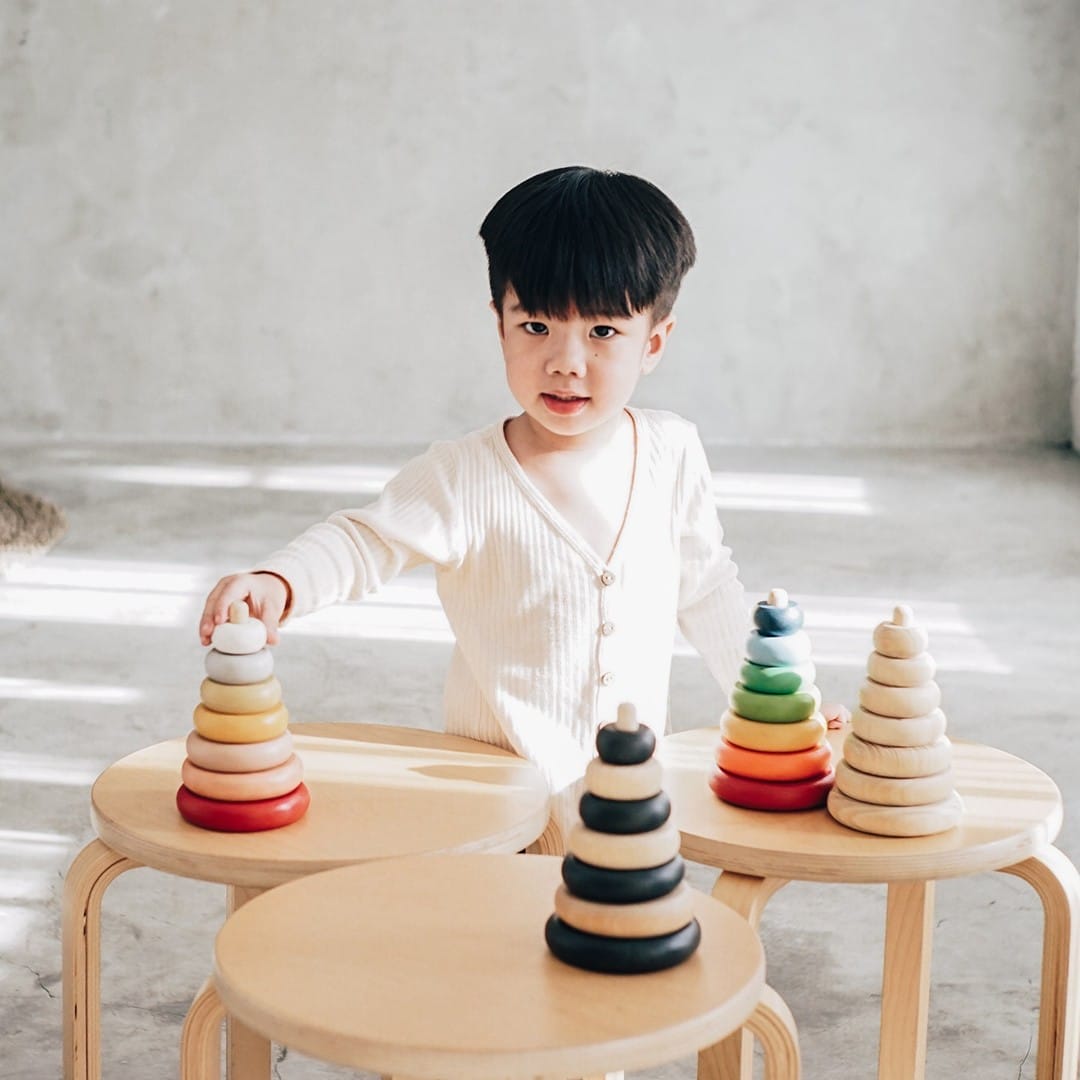 little boy playing with wooden stacking rings