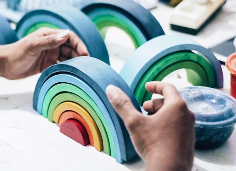 Toymaker making wooden rainbow toy
